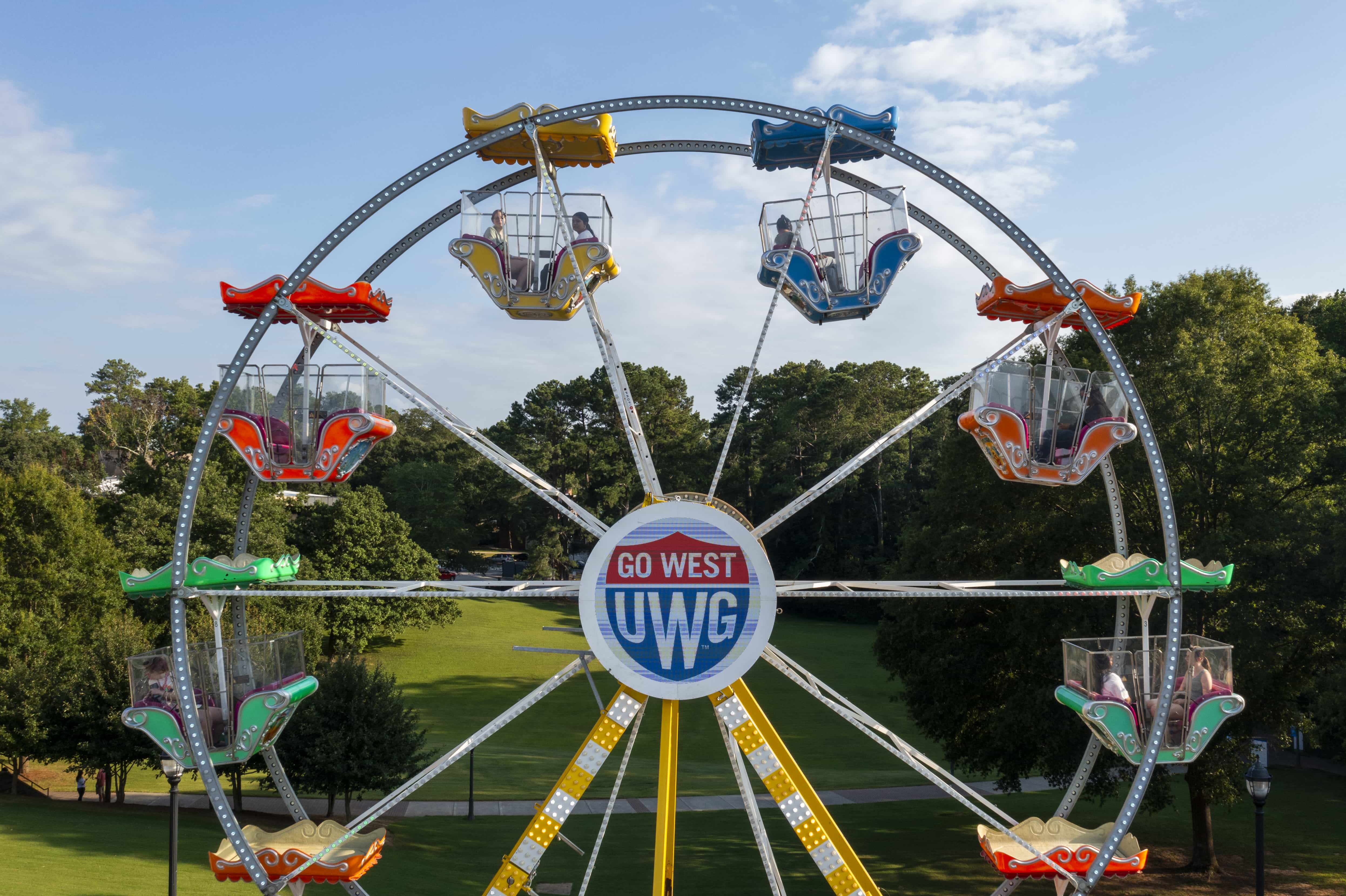 UWG branded ferris wheel with LED Shield logo lit up in the center, set up in Love Valley.