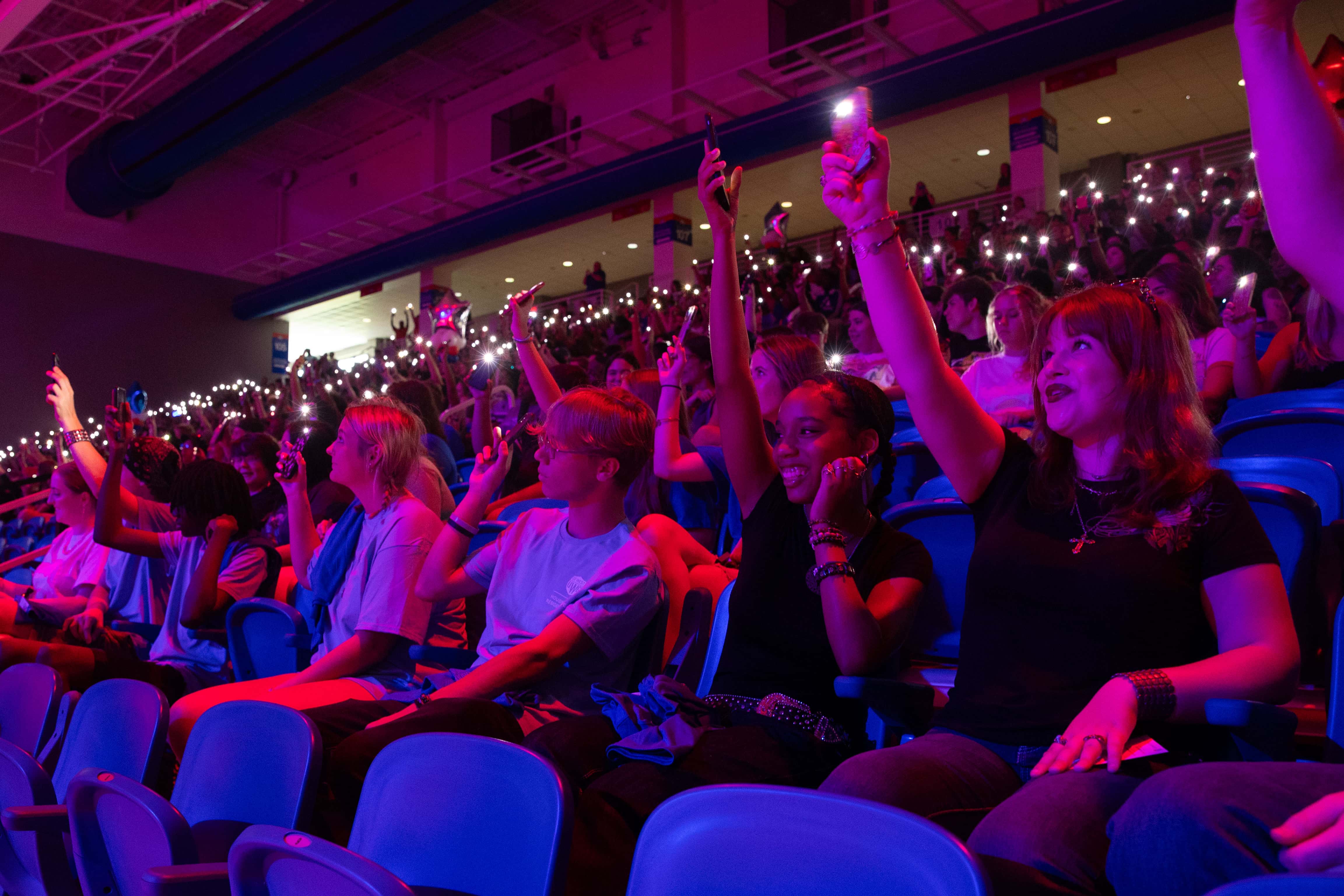 Students gathered in The Coliseum shining phone lights with blue and red lighting washing over the crowd.