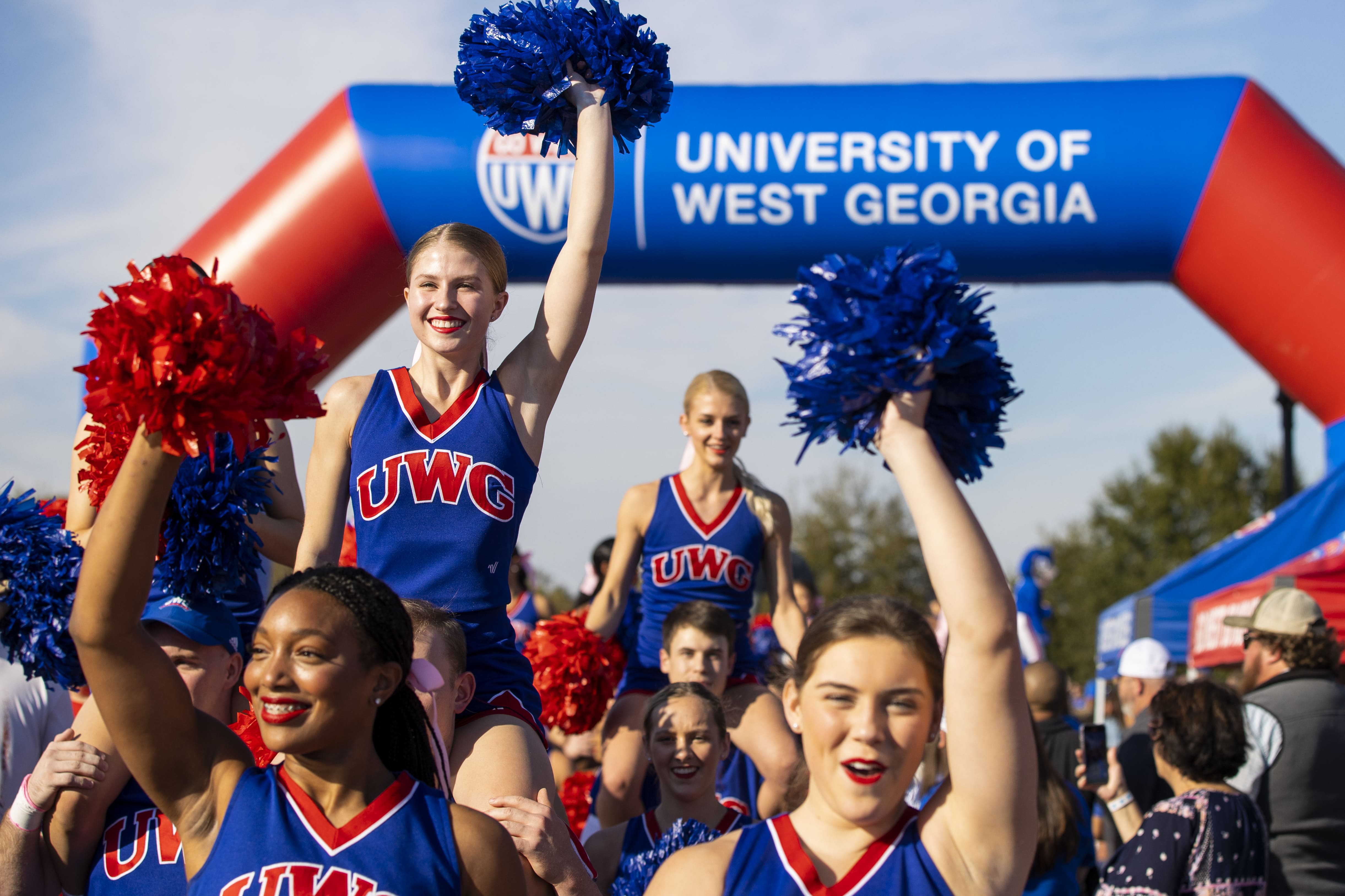 Cheerleaders walking through a crowd, leading the football team into the University Stadium on game day!