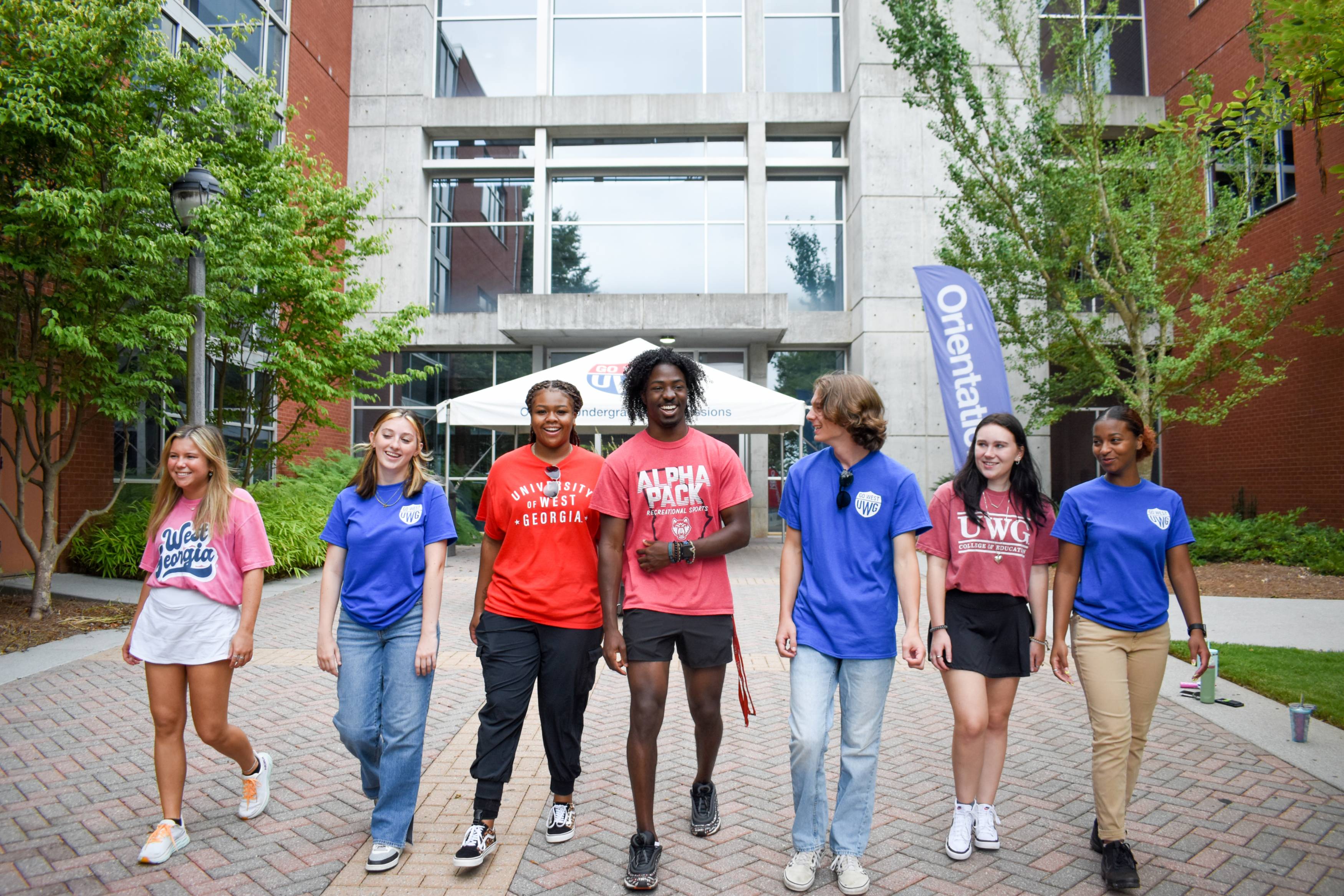 Students walking on the pedestrian in front of the Dr. James "Earl" Perry Building in a line, smiling and laughing.