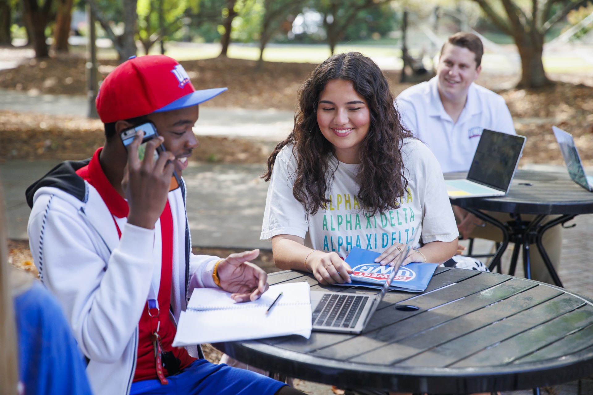 Students sitting in at an outdoor table working thorugh application information.