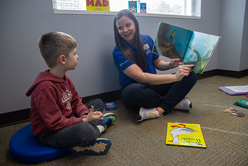Tutor point at a childrens book while chiild engages