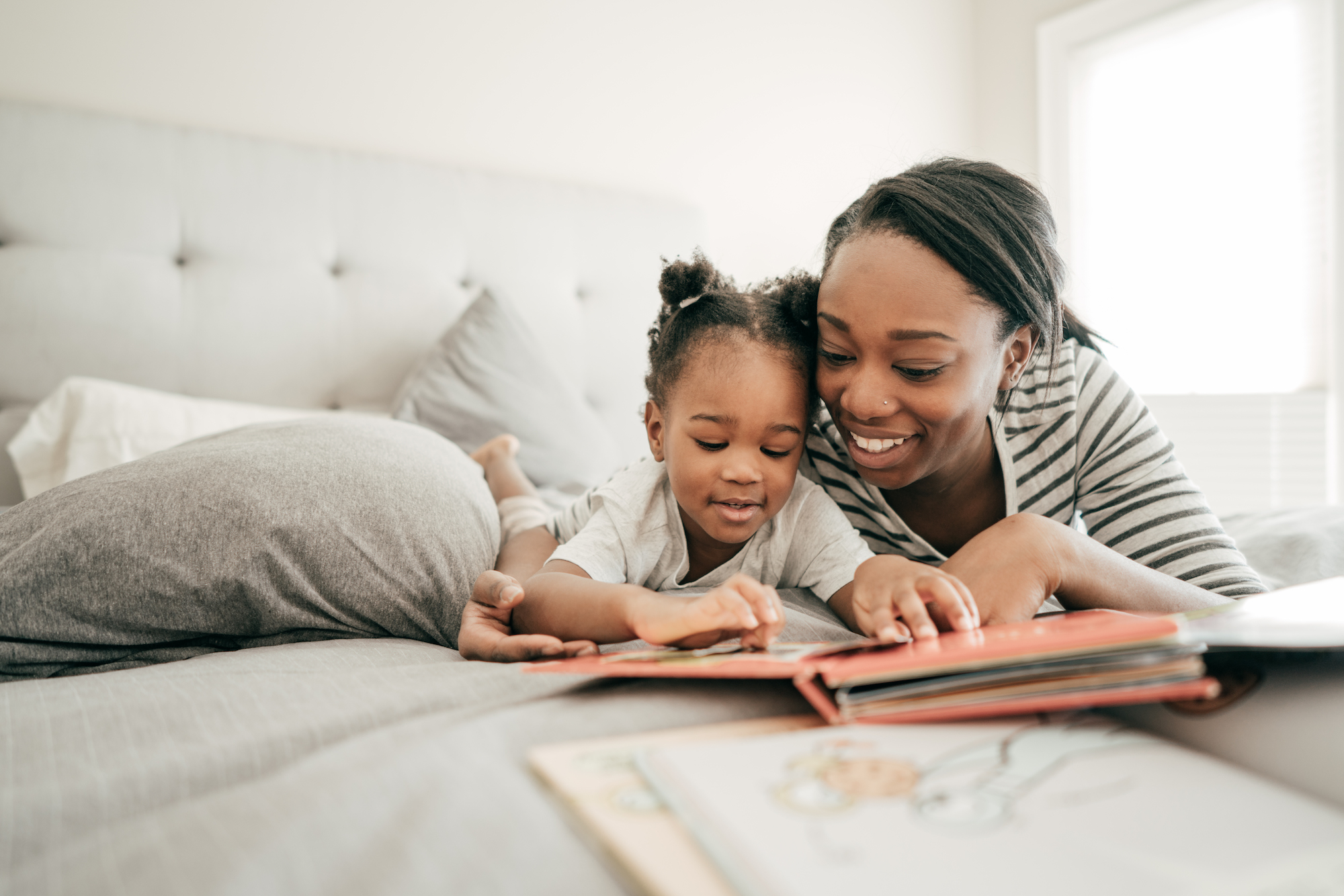 A mom and daughter reading in bed together.