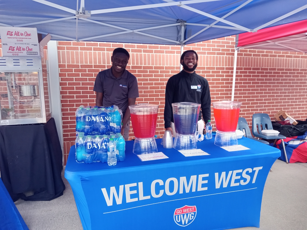 Peer Educators at tabling event standing behind a table smiling together.