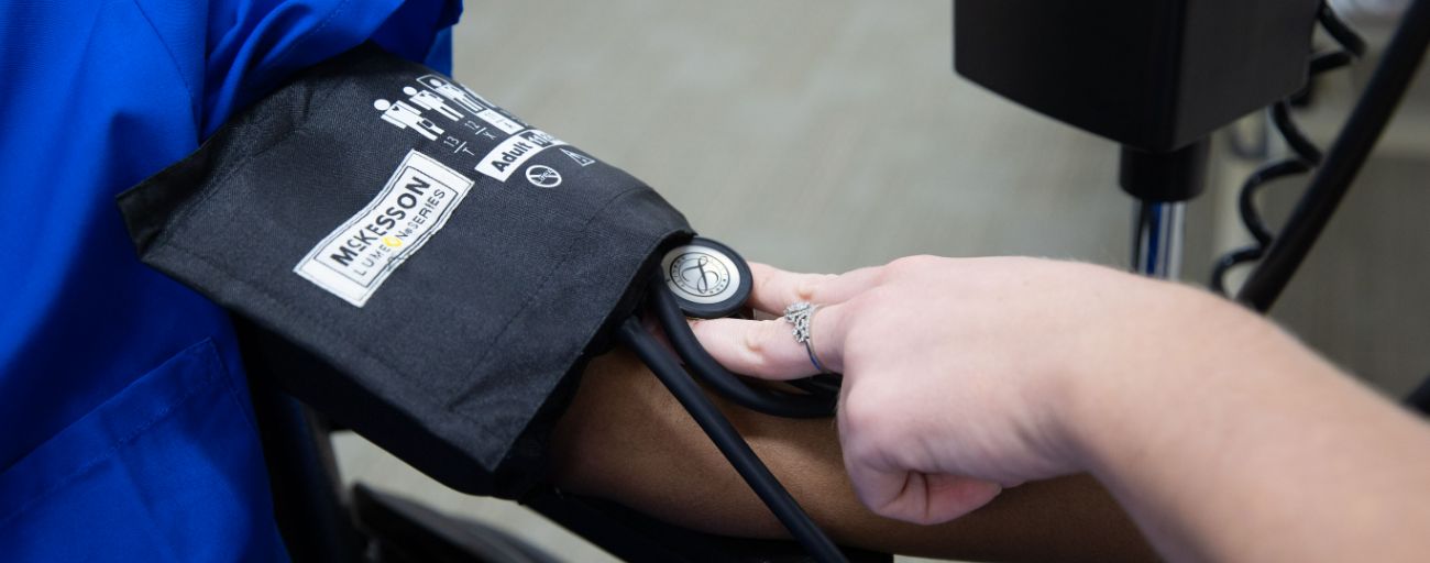 cna taking blood pressure of patient