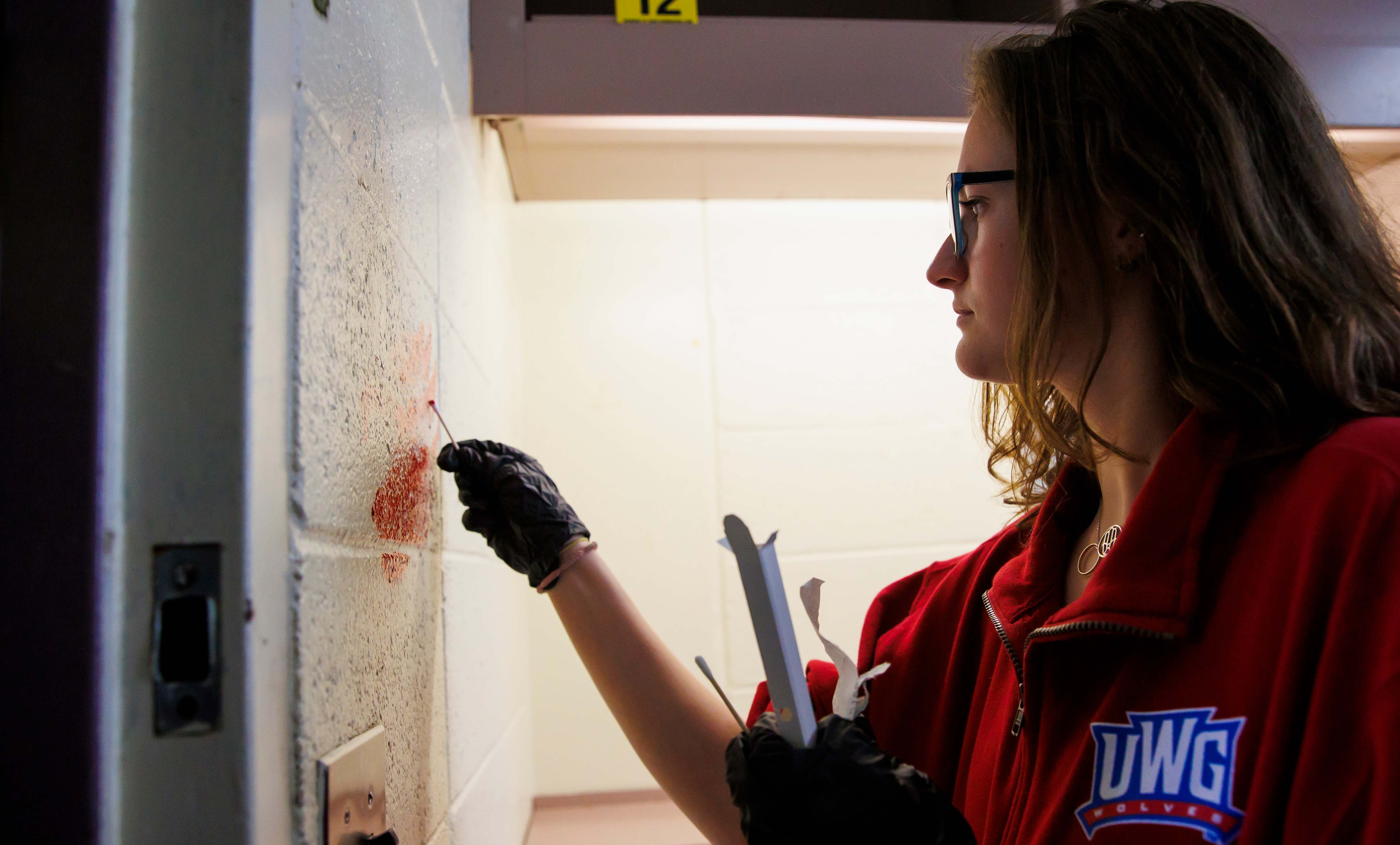 Student swabbing a stain on a wall.