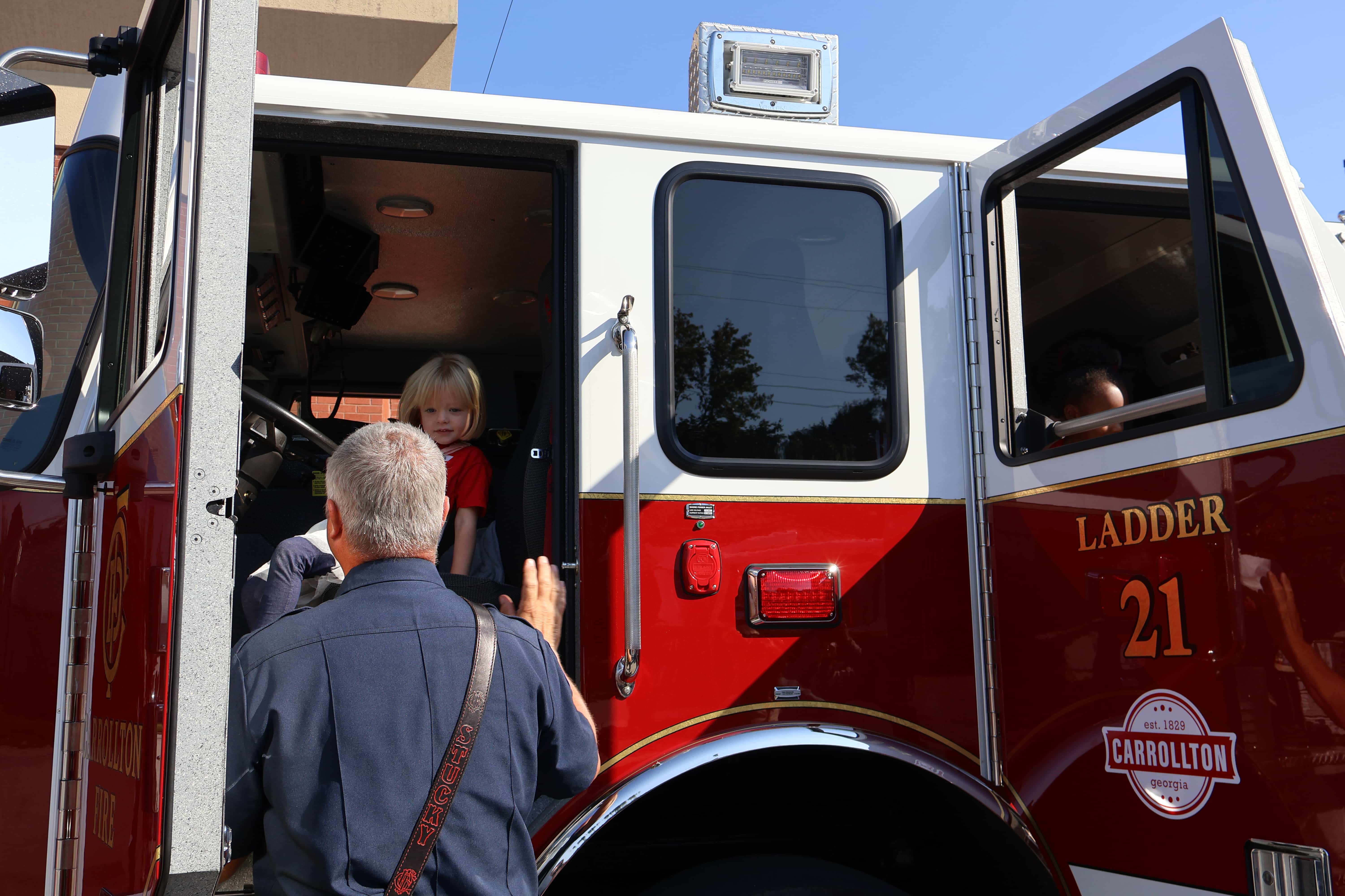 Pre-K student sitting in the drivers seat of a firetruck.