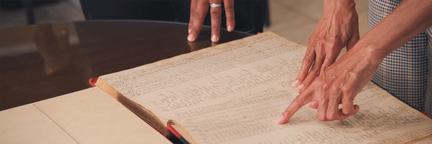 People reading through an old manuscript with a closeup on the hands