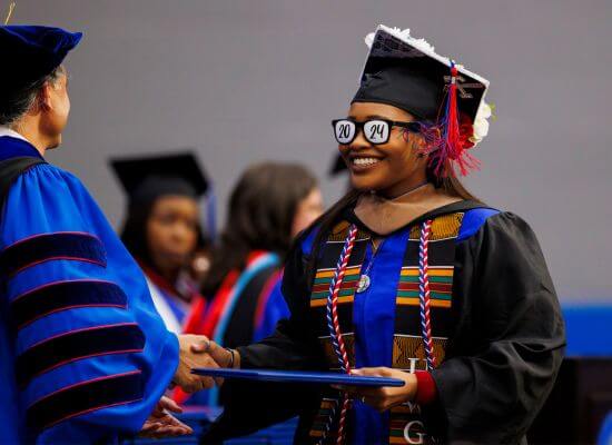 A UWG graduate with 2024 glasses accepts her degree