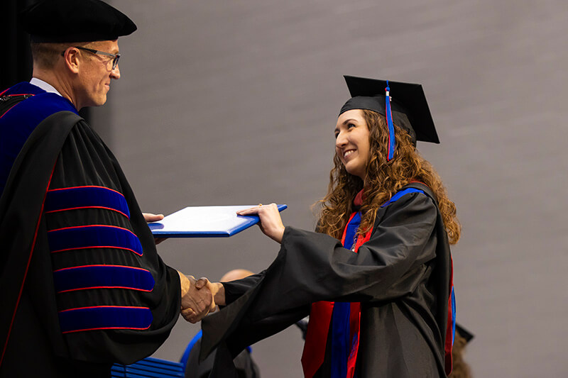 Dr. Brendan Kelly, UWG president, hands a graduate her degree