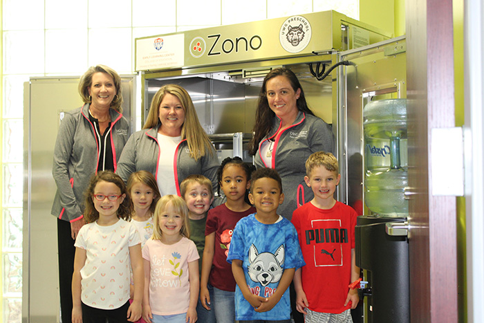 Teachers and students in front of a ZONO Technologies ozone disinfecting and sanitizing cabinet 