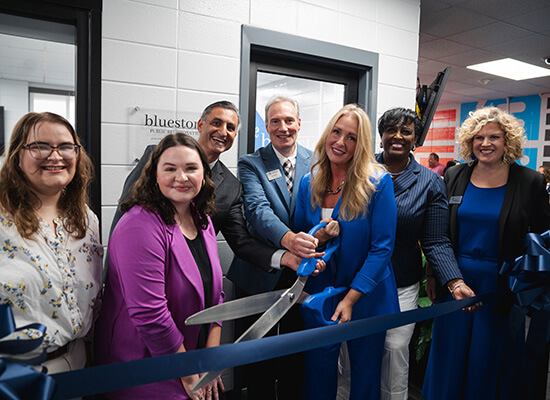 People gather at a ribbon-cutting ceremony celebrating UWG's student-run public relations firm, bluestone.